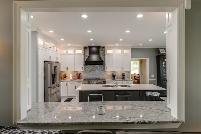 kitchen with custom range hood, white cabinetry, light stone counters, sink, and high end refrigerator