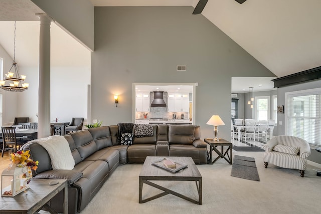 living room with high vaulted ceiling, light carpet, and a chandelier