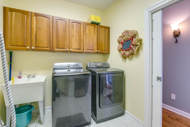 laundry area featuring light hardwood / wood-style floors, independent washer and dryer, and cabinets