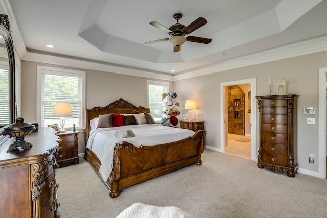 bedroom featuring a raised ceiling, ensuite bath, and light carpet