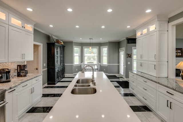 kitchen featuring backsplash, light tile patterned floors, sink, decorative light fixtures, and crown molding