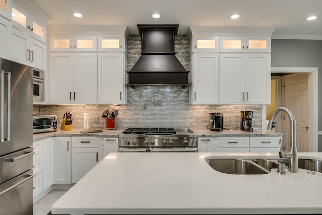 kitchen featuring backsplash, sink, custom range hood, high end appliances, and white cabinetry