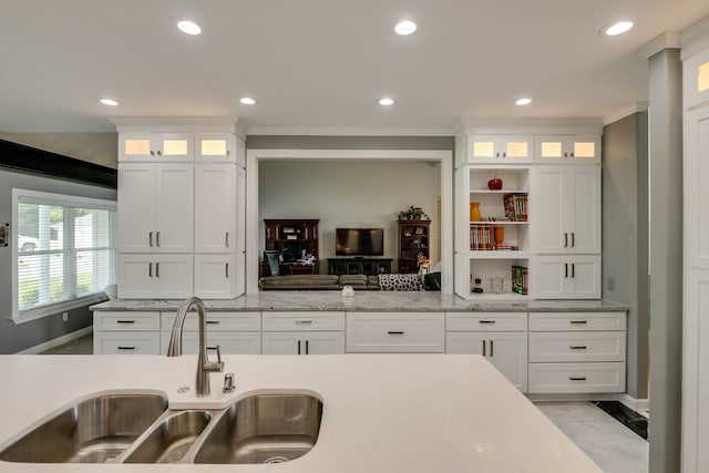 kitchen featuring sink, light stone counters, crown molding, white cabinets, and light tile patterned flooring