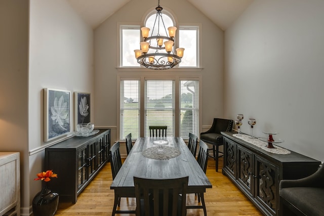 dining space with light hardwood / wood-style flooring, high vaulted ceiling, and an inviting chandelier