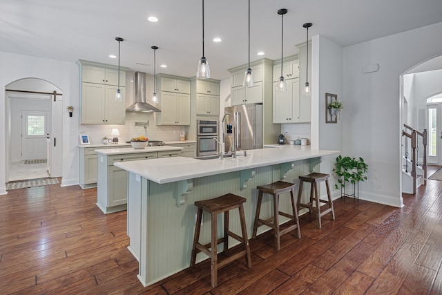 kitchen featuring a kitchen breakfast bar, dark hardwood / wood-style flooring, wall chimney exhaust hood, stainless steel appliances, and kitchen peninsula