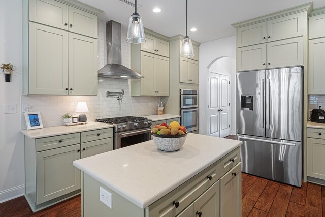 kitchen featuring stainless steel appliances, decorative backsplash, wall chimney range hood, a center island, and dark wood-type flooring