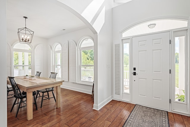 foyer entrance with dark hardwood / wood-style flooring, an inviting chandelier, and a wealth of natural light