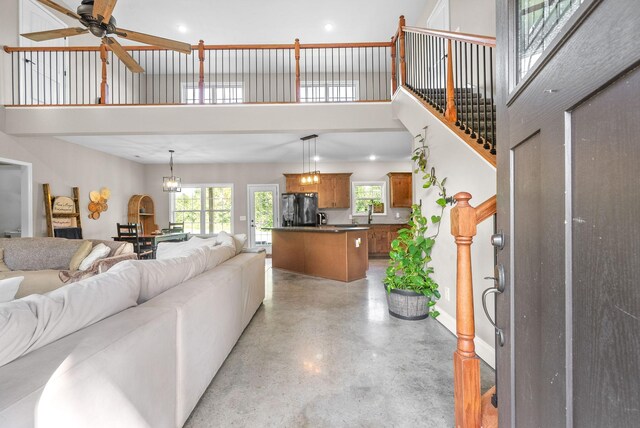 living room featuring a towering ceiling and ceiling fan with notable chandelier