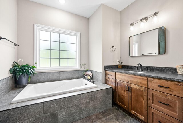 bathroom featuring tile patterned flooring, tiled tub, and vanity