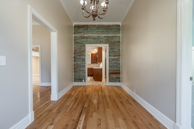 corridor featuring crown molding, light hardwood / wood-style floors, and a chandelier