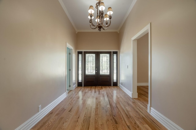 entrance foyer with light wood-style flooring, a notable chandelier, baseboards, french doors, and ornamental molding