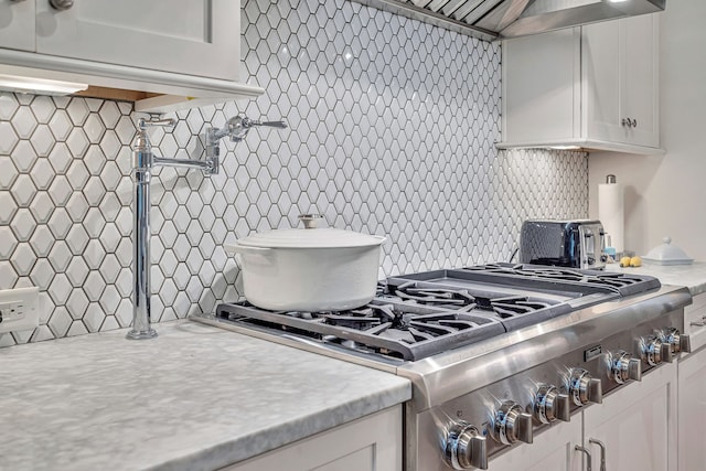 kitchen featuring white cabinets, stainless steel range oven, and decorative backsplash