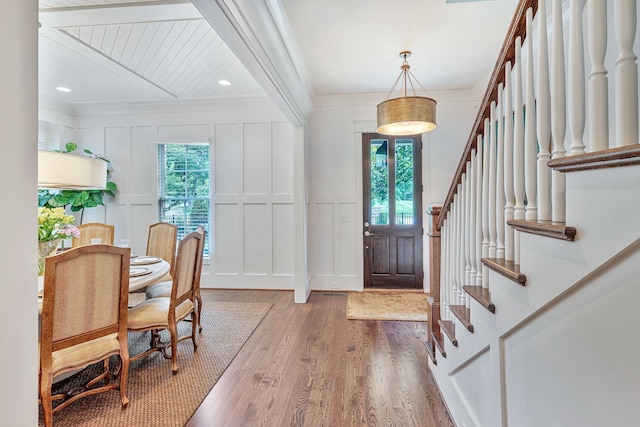 foyer featuring ornamental molding, beamed ceiling, and hardwood / wood-style flooring