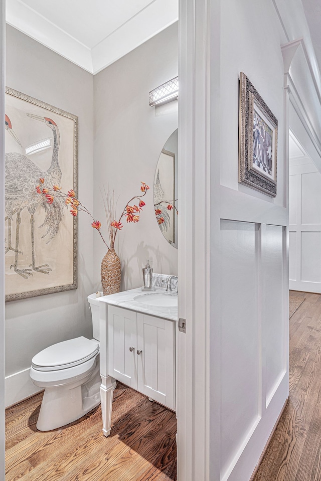 bathroom featuring hardwood / wood-style floors, toilet, crown molding, and vanity