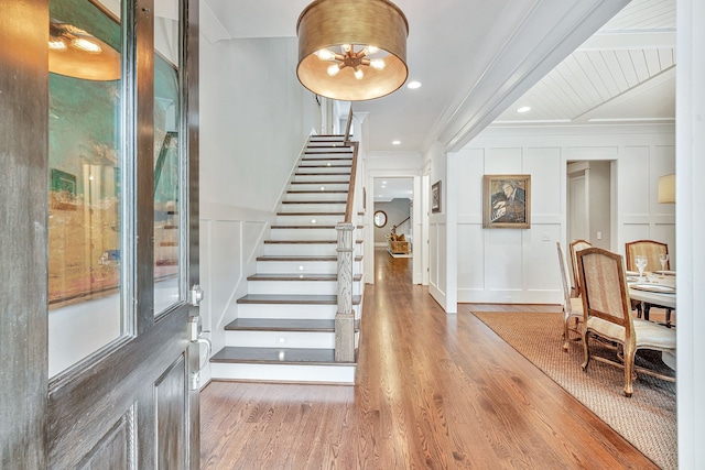 foyer featuring ornamental molding, wood-type flooring, and a chandelier