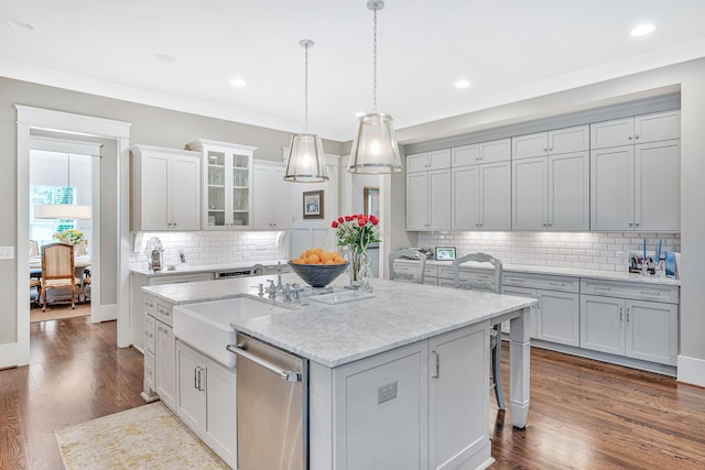 kitchen with a kitchen island with sink, crown molding, dishwasher, dark hardwood / wood-style flooring, and sink