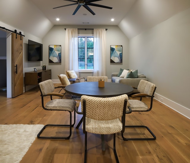 dining room with ceiling fan, lofted ceiling, a barn door, and wood-type flooring