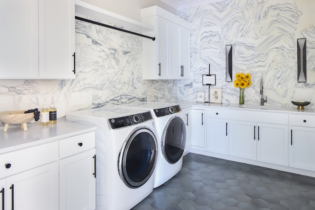 washroom with sink, washing machine and clothes dryer, cabinets, and dark tile patterned floors