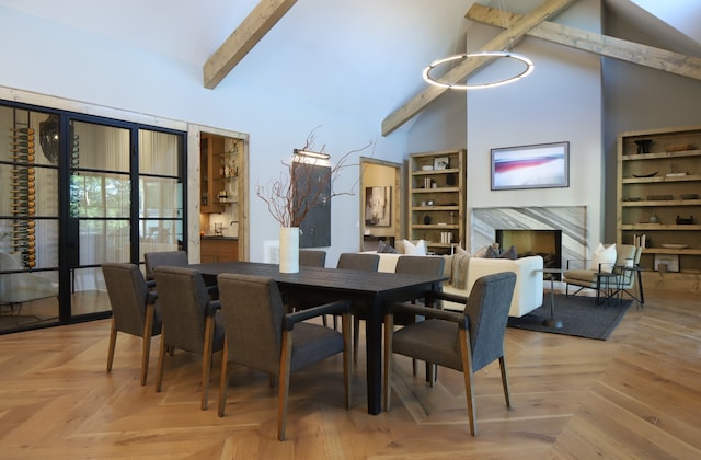 dining space with beam ceiling, high vaulted ceiling, and light parquet floors