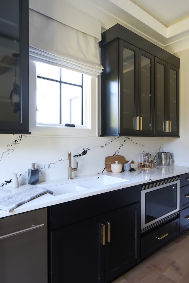 kitchen featuring tasteful backsplash, sink, light stone counters, stainless steel microwave, and dark hardwood / wood-style flooring