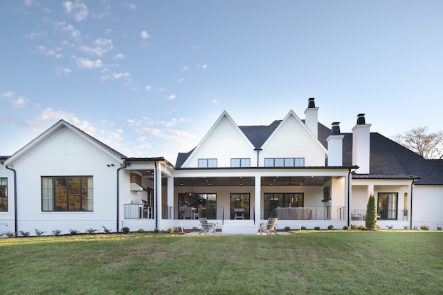 rear view of property featuring ceiling fan and a yard