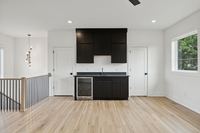 kitchen with sink, decorative light fixtures, light hardwood / wood-style floors, and wine cooler