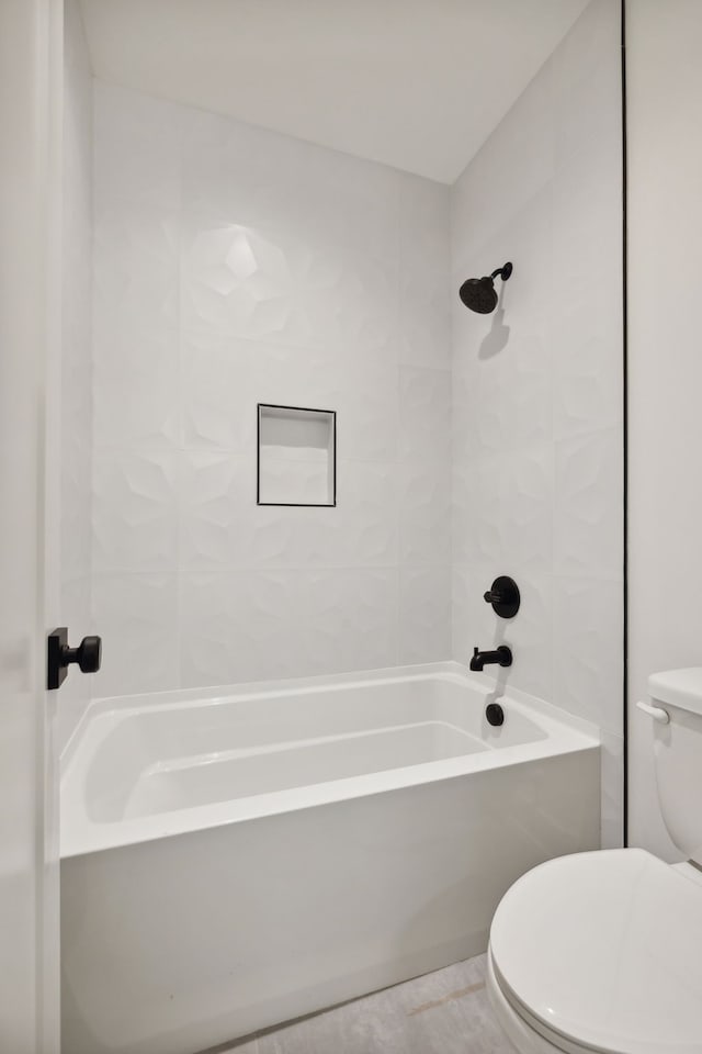 bathroom featuring tiled shower / bath combo, toilet, and tile patterned flooring