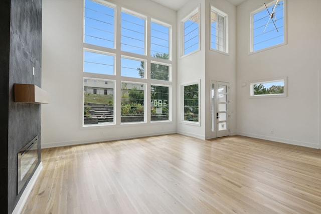 unfurnished living room featuring light hardwood / wood-style floors and a towering ceiling