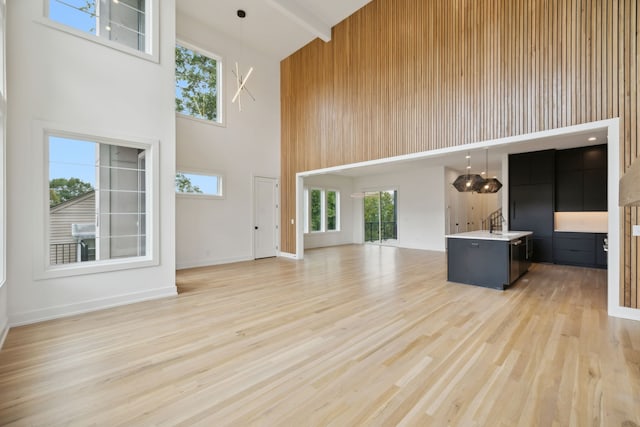 unfurnished living room with light hardwood / wood-style floors and a high ceiling