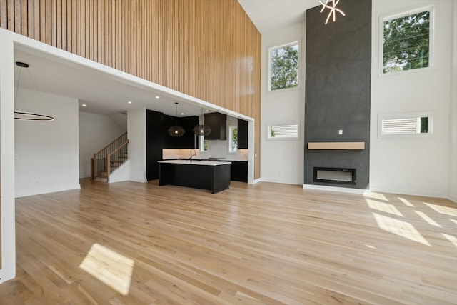 unfurnished living room with light hardwood / wood-style floors, a towering ceiling, sink, and a fireplace