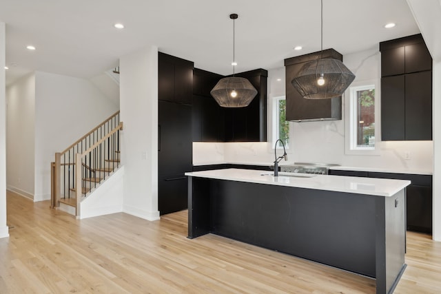 kitchen with a kitchen island, light hardwood / wood-style flooring, decorative light fixtures, and sink