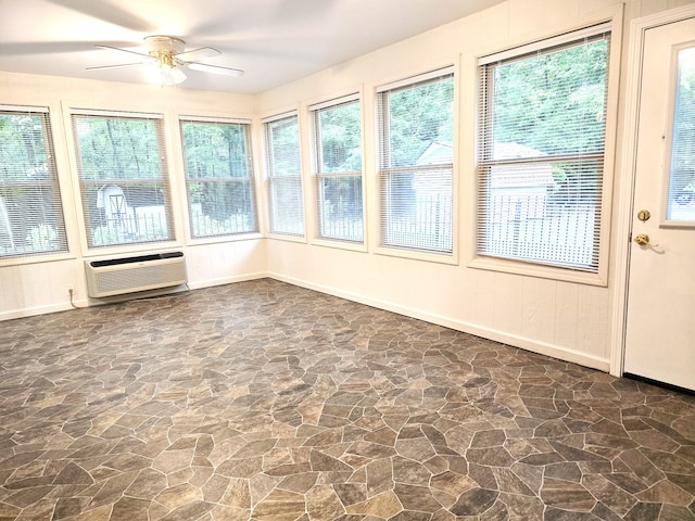 unfurnished sunroom featuring ceiling fan, a healthy amount of sunlight, and a wall mounted air conditioner