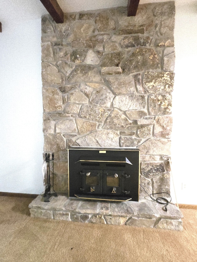 details featuring beamed ceiling, carpet floors, and a stone fireplace