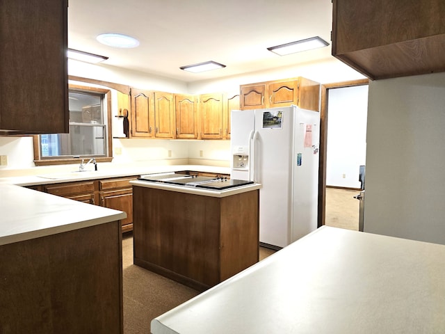 kitchen with a center island, cooktop, white refrigerator with ice dispenser, and sink