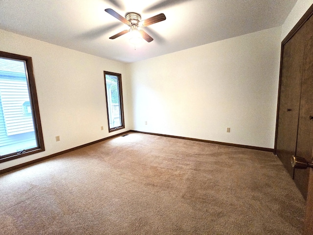 carpeted spare room featuring ceiling fan