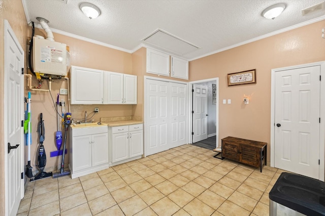 kitchen featuring crown molding, light countertops, visible vents, tankless water heater, and white cabinets