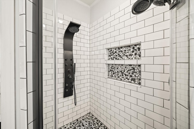 bathroom with a tile shower and crown molding