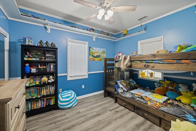 bedroom featuring light wood-style flooring, a textured ceiling, visible vents, and crown molding