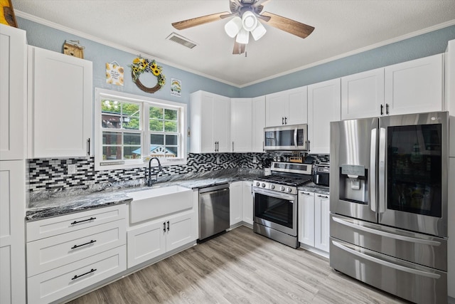 kitchen with white cabinetry, appliances with stainless steel finishes, a sink, and ornamental molding