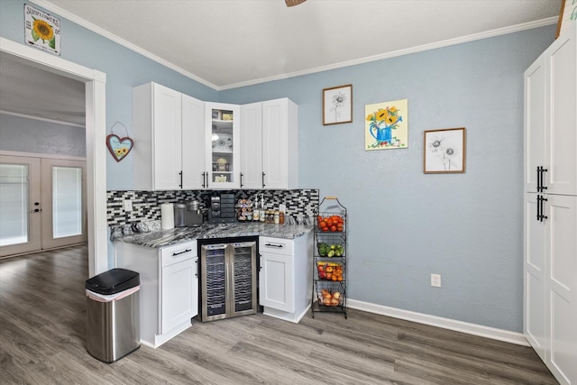 kitchen with glass insert cabinets, dark stone counters, beverage cooler, and white cabinetry