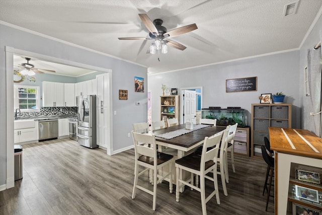 dining room with ornamental molding, visible vents, a textured ceiling, and light wood finished floors