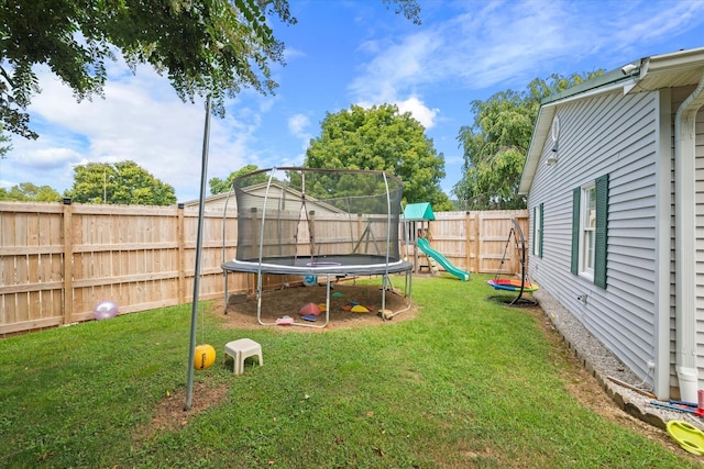 view of yard with a trampoline, a playground, and a fenced backyard