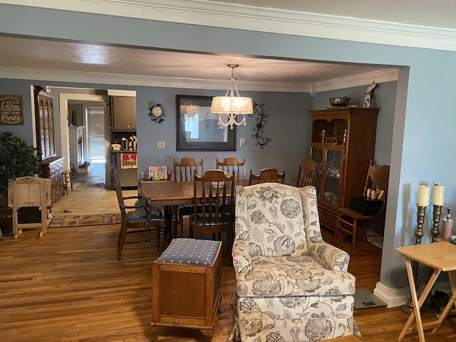 dining area featuring an inviting chandelier, crown molding, and wood finished floors