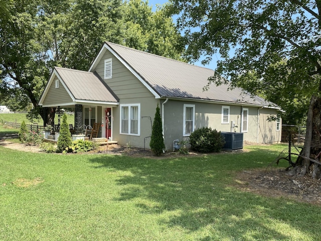 view of front of home featuring metal roof, a porch, a front yard, and stucco siding