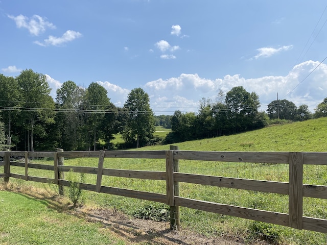 view of gate with a rural view and a lawn