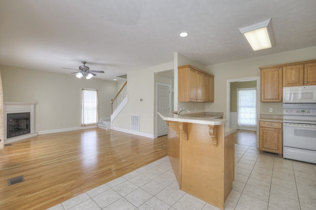 kitchen featuring light tile patterned floors, a breakfast bar area, plenty of natural light, and white appliances