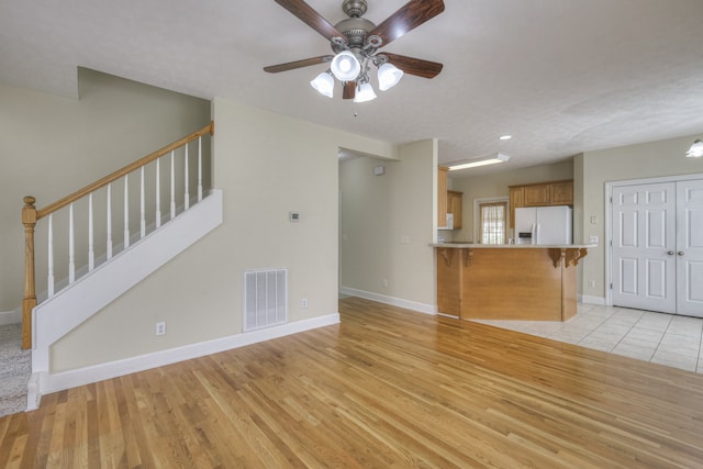 unfurnished living room featuring ceiling fan and light wood-type flooring