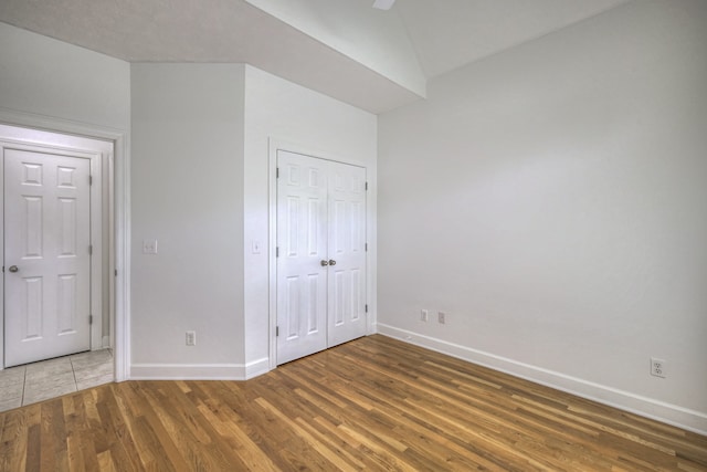 unfurnished bedroom with ceiling fan, a closet, vaulted ceiling, and wood-type flooring