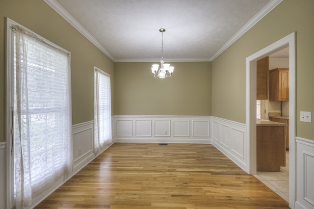 unfurnished dining area with light hardwood / wood-style flooring, a chandelier, and ornamental molding