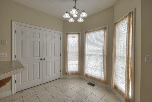 unfurnished dining area with light tile patterned flooring, a healthy amount of sunlight, and a chandelier